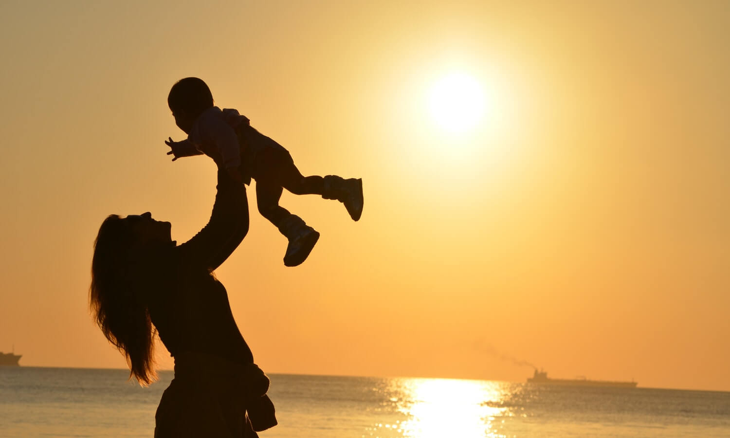 woman-carrying-baby-at-beach-during-sunset
